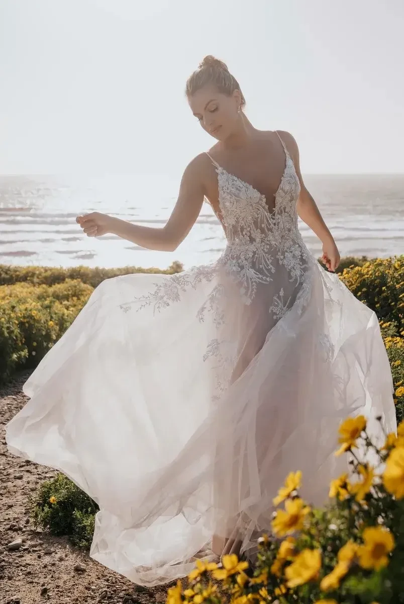 Model is wearing an a-line wedding gown with a dropped waist and lace appliques by allure bridals