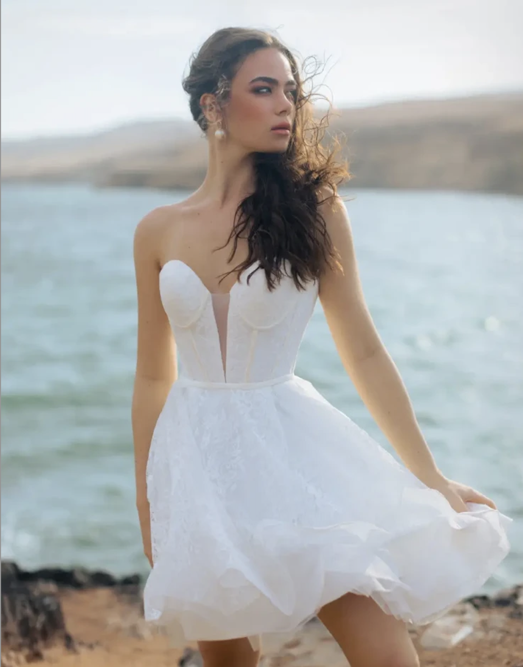 Model is wearing a strapless A-line mini dress with a plunge neckline, layered skirt, and lace floral motifs for a fresh, playful look.